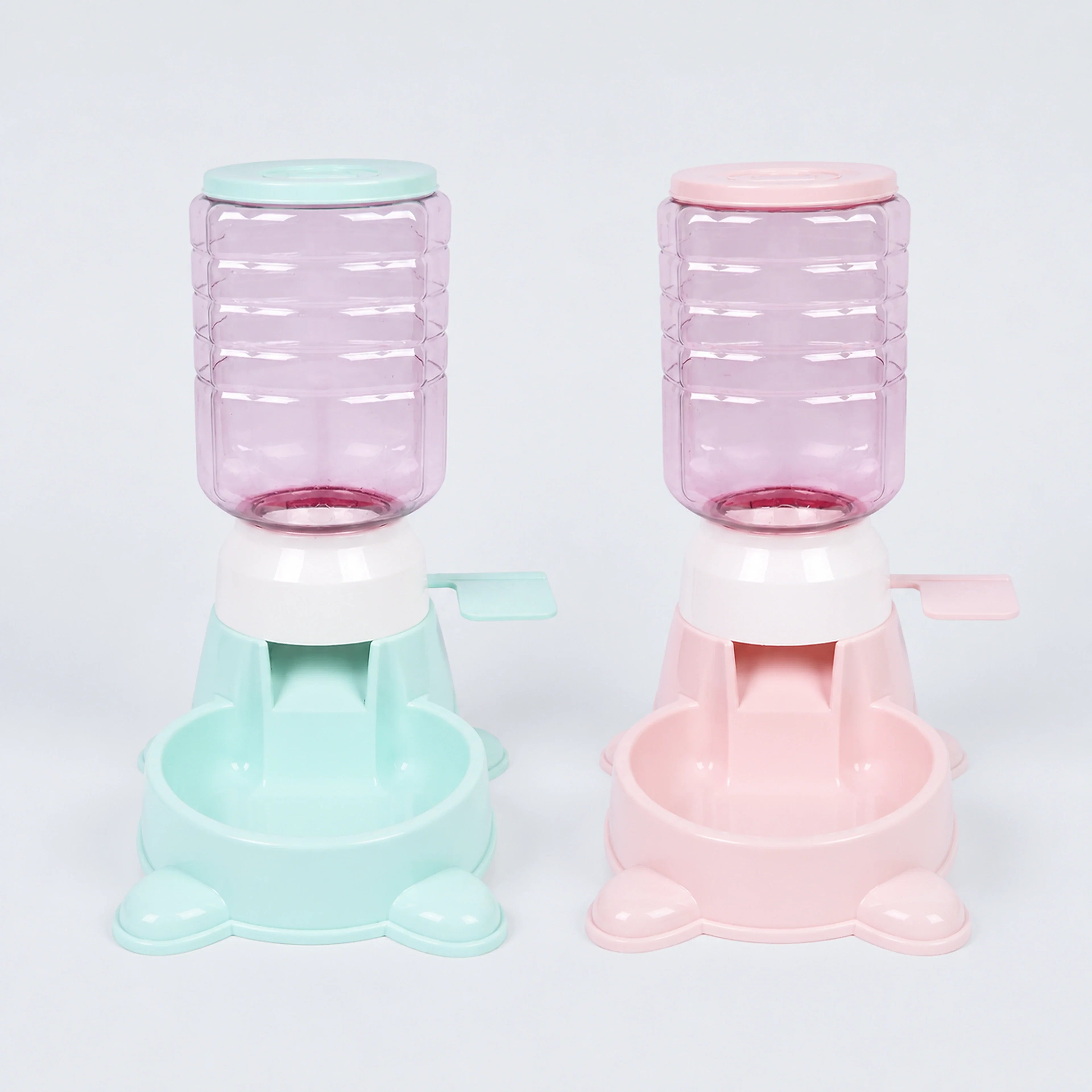 Mint green and pale pink 1.8 L paw-press interactive pet feeders on a cool gray-blue background