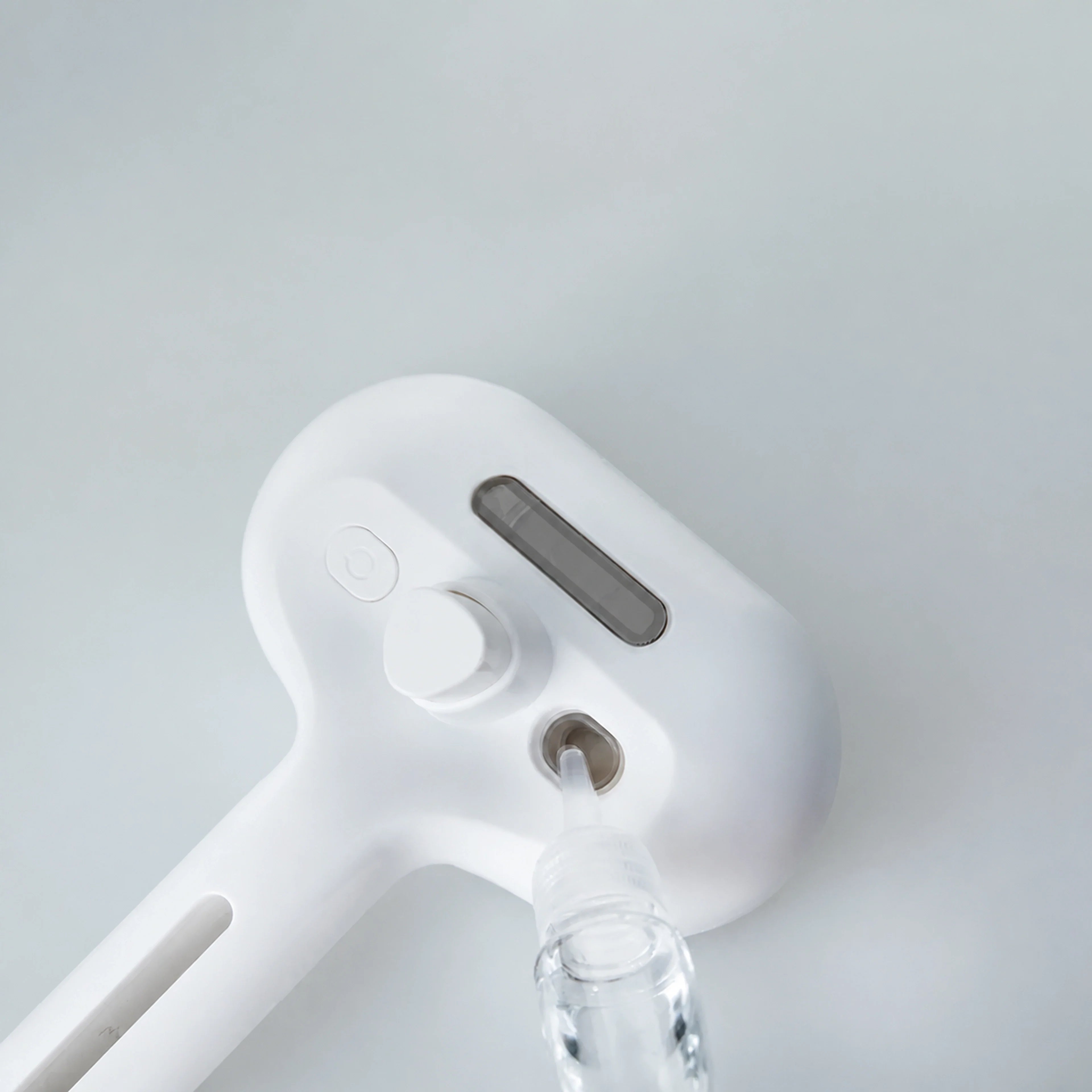 White self-cleaning pet grooming brush showing transparent water reservoir opening